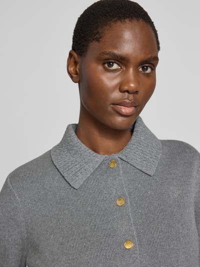 Frauenmodel trägt Strickjacke aus Baumwoll-Woll-Mix von Tommy Hilfiger in Grau mit Zierknöpfen und Brusttasche, Nahaufnahme Oberkörper.