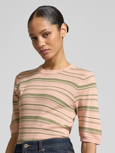 Frauenmodel trägt Strickpullover aus Baumwoll-Mix von Scotch & Soda in Rosa mit grünen Streifen, taillierte Passform, Nahaufnahme Oberkörper.