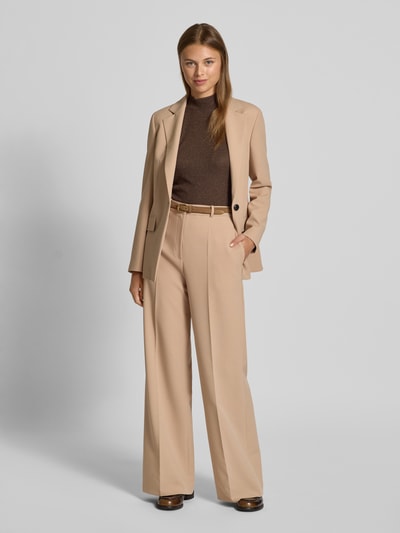 Frauenmodel trägt schimmerndes Top aus Viskose-Mix mit Stehkragen von Rich & Royal, braun, kombiniert mit beigefarbenem Anzug, Ganzkörperansicht von vorne. Slim Fit, Stretch-Anteil, Rückenlänge bei Größe S 60 cm.