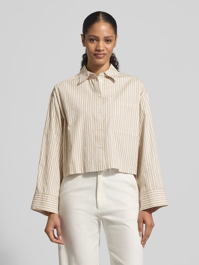 Vrouwenmodel draagt Oversized Hemdbluse aus reiner Bio-Baumwolle Modell 'Astha' van Selected Femme, look: effen, oversized fit, overhemdkraag, achterpas met Cacharel-plooi, verlaagde schouders, knoopsluiting, mouwboord met manchet, borstzak, geweven biologisch katoen, crèmekleurige strepen, textuur: glad, rechte vorm, volledige vooraanzicht.