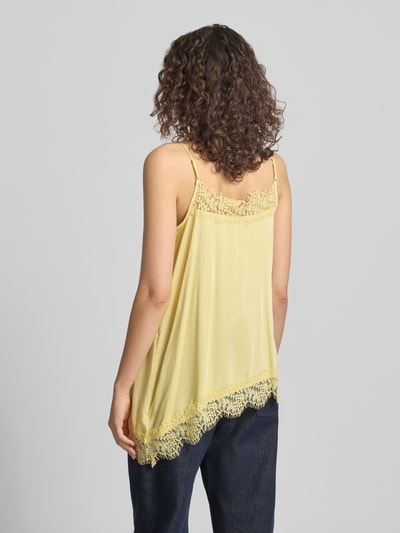 Frauenmodel trägt Relaxed Fit Top mit Spitzenbesatz Modell 'Tami' von OH APRIL in Gelb aus Satin mit Spaghetti-Träger, Asymmetrisches Design, Ganzkörperansicht Rückansicht.