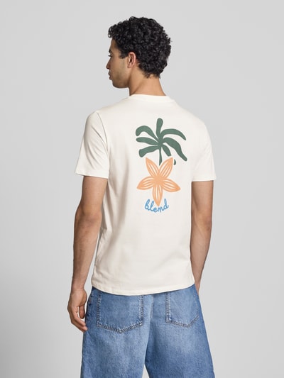 Männermodel trägt T-Shirt mit Motiv-Print Modell 'SUN PALMS' von Blend in Creme mit grünem und orangem Print, Baumwolle, Regular Fit, Ganzkörperansicht Rückansicht.