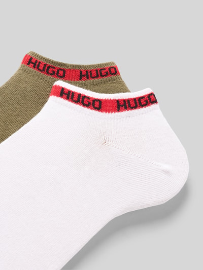Produktfoto, zwei Paar Socken aus Baumwoll-Mix von HUGO in Weiß und Olivgrün mit rotem HUGO-Schriftzug, glatte Textur, Herren Socken.