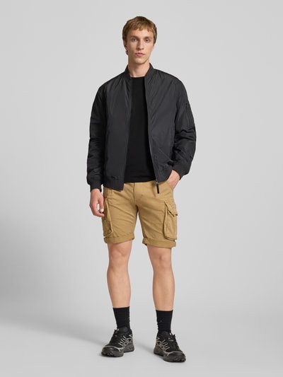 Männermodel trägt T-Shirt mit Logo und Rundhalsausschnitt von Alpha Industries, Reine Baumwolle, Regular-Fit, schwarze Farbe, Ganzkörperansicht von vorne.