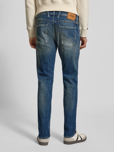 Männermodel trägt Slim Fit Jeans aus Baumwoll-Mix im Destroyed-Look von Replay, blaue Waschung, Kontrastnähte, Ganzkörperansicht Rückansicht. 5-Pocket-Design, Herren Jeans, Knopf- und Reißverschluss, Bundweite 44 cm, Innenbeinlänge 82 cm.
