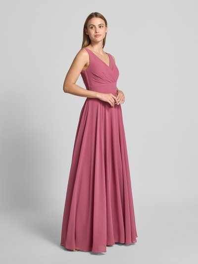 Frauenmodel trägt Maxikleid aus Chiffon in Wickel-Optik von TROYDEN COLLECTION in A-Linie, mattes Rosa, fließende Textur, Ganzkörperansicht von vorne.