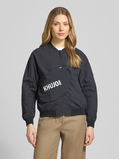 Frauenmodel trägt Jacke mit Pattentaschen Modell 'FACEE' von khujo in Schwarz, Regular-Fit, Stehkragen, Reißverschluss, Umhängetasche, Nahaufnahme Oberkörper. Rückenlänge bei Größe S: 60 cm, Schulterbreite: 50 cm, Brustweite: 55 cm, Ärmellänge: 56 cm.