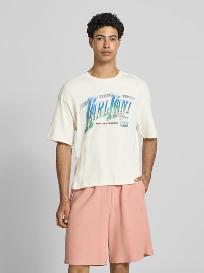 Männermodel trägt T-Shirt mit Label-Print Modell 'Sport Gradient' von KARL KANI aus reiner Baumwolle, Boxy Fit, Nahaufnahme Oberkörper.