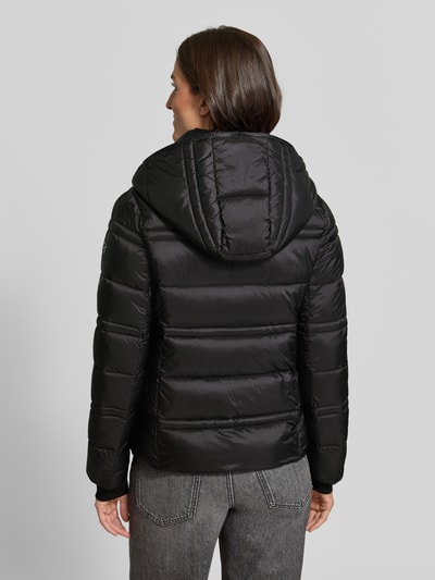 Vrouwenmodel draagt Steppjacke met Kapuze en Reißverschlusstaschen van MICHAEL Michael Kors in zwart, doorgestikte naden, recht model, Ganzkörperansicht Rückansicht. Ruglengte maat S: 63 cm, schouderbreedte 43 cm, borstwijdte 53 cm, mouwlengte 68 cm.