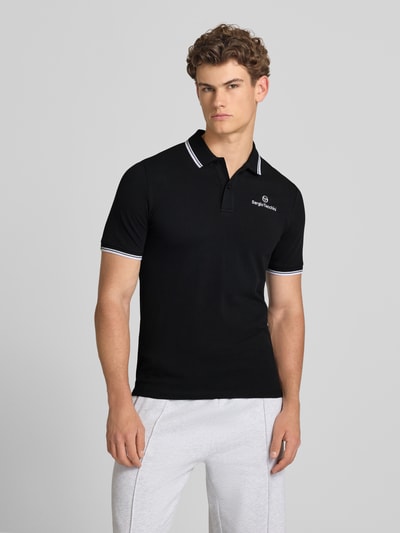 Männermodel trägt Slim Fit Poloshirt mit Logo-Stitching Modell 'Reed' von SERGIO TACCHINI, Schwarz, Baumwoll-Mix, Ganzkörperansicht von vorne.