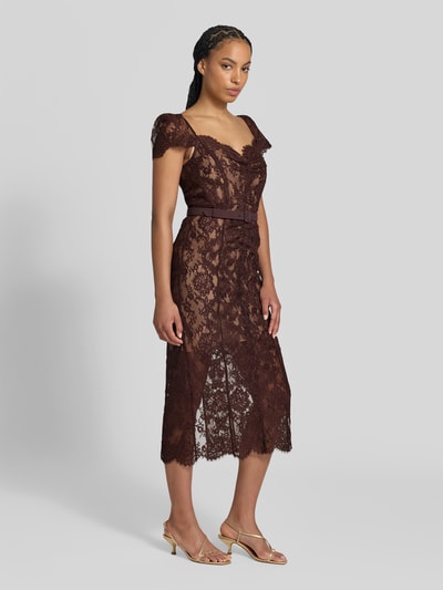 Frauenmodel trägt Midikleid mit Allover-Spitzenbesatz von Self-Portrait in Braun, taillierte Passform, Taillengürtel, Kurzarm, Baumwolle, Ganzkörperansicht von vorne.
