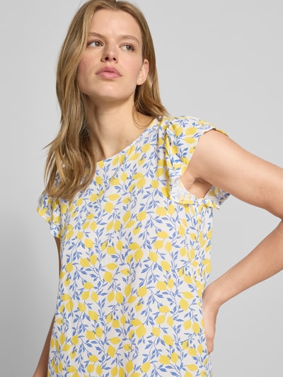 Frauenmodel trägt Regular Fit Sommerkleid aus reiner Viskose Modell 'BARRI' von Pieces, Optik:Allover-Muster in Gelb und Blau, Kurzarm, Schmetterlingsärmel, Crêpe-Material, Rundhals-Ausschnitt, Knopf mit Öse, Nahaufnahme Oberkörper.