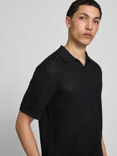 Męski model nosi Regular Fit Poloshirt mit V-Ausschnitt von Jack & Jones, bawełna, czarny, krój regular fit, długość tyłu 67 cm, półzbliżenie przód.