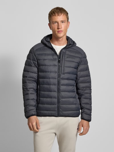 Mannelijk model draagt Gewatteerd jack met capuchon en logo van CHAMPION in regular fit, donkergrijs, ritssluiting, steekzakken, Ganzkörperansicht van voren. Ruglengte maat M: 71 cm, schouderbreedte: 51 cm, borstwijdte: 61 cm, mouwlengte: 69 cm.