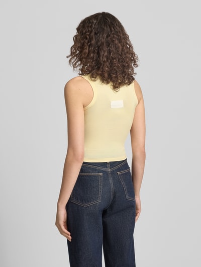 Frauenmodel trägt Slim Fit Top mit Logo-Detail von ANOTHER COTTON LAB in Hellgelb, elastischer Baumwoll-Mix, Rückenansicht Ganzkörperansicht.