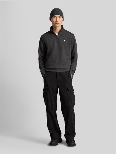 Männermodel trägt Relaxed Fit Troyer aus Baumwoll-Mix von Polo Ralph Lauren in dunklen Farben, Ganzkörperansicht von vorne.