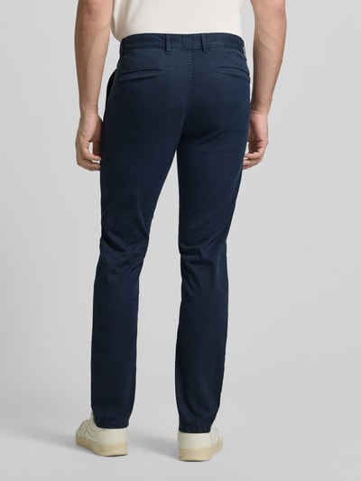 Männermodel trägt Slim Fit Chino aus Baumwoll-Mix Modell 'CHINO_SLIM' von BOSS Orange mit feinem Strukturmuster, Ganzkörperansicht Rückansicht.