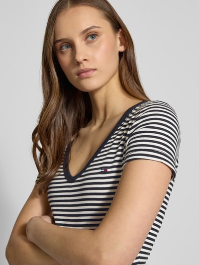 Vrouwenmodel draagt Slim Fit T-Shirt aus Baumwoll-Mix van Tommy Jeans, two tone, logo-stitching, v-hals, korte mouw, ribstof, katoenmix. Close-up bovenlichaam.