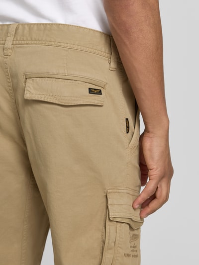 Männermodel trägt Bermudas mit Pattentaschen und Label-Stitchings von PME Legend in Beige, Motiv- und Label-Stitchings, Nahaufnahme Oberkörper, seitliche Eingrifftaschen, Knopf- und Reißverschluss, Klettverschluss, Straight Fit, Bundweite 41 cm, Innenbeinlänge 26 cm, Größe 32.