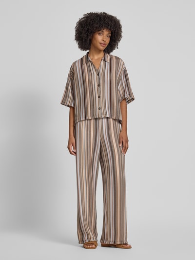 Frauenmodel trägt Boxy Fit Bluse mit V-Ausschnitt von Smith and Soul aus Material-Mix mit Stretch-Anteil, Allover-Look, Hemblusenkragen, Knopfleiste, gestreiftes Muster in Beige, Braun und Schwarz, Ganzkörperansicht von vorne.