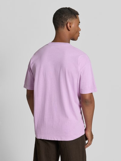 Mannelijk model draagt oversized T-shirt van puur katoen Modell 'Joel' van Samsøe Samsøe, lila, logo-print, ronde hals, ruglengte 72 cm, Ganzkörperansicht Rückansicht.