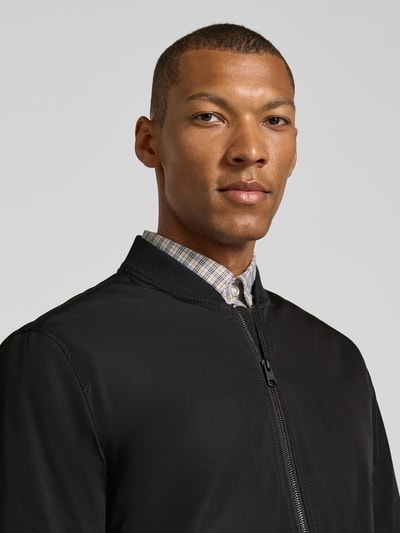 Männermodel trägt Regular Fit Jacke mit Stehkragen Modell 'Rapid' von CINQUE in Schwarz, glatte Struktur, Nahaufnahme Oberkörper. Rückenlänge 70 cm, Schulterbreite 49 cm, Brustweite 59 cm, Ärmellänge 69 cm, Zweiwege-Reißverschluss, elastische Abschlüsse, Eingrifftaschen.