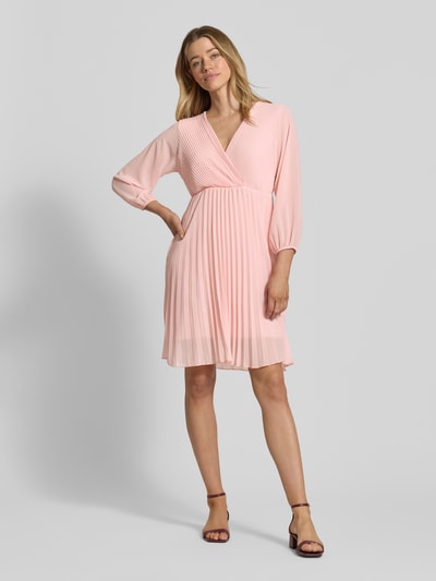 Frauenmodel trägt Knielanges Kleid mit Plisseefalten Modell 'Im44sa' von ZABAIONE, Taillierter Schnitt, Wickel-Optik, zartrosa, Ganzkörperansicht von vorne. Rückenlänge bei Größe S: 90 cm, Brustweite bei Größe S: 38 cm, Ärmellänge bei Größe S: 52 cm.