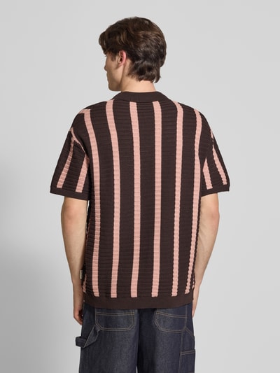 Männermodel trägt Regular Fit Strick-Poloshirt Modell 'POUL' von Redefined Rebel, Baumwoll-Mix, breite rosa-braune Streifen, Ganzkörperansicht Rückansicht. Rückenlänge 66 cm in Größe M, Knopfleiste sichtbar, Strickstruktur deutlich.