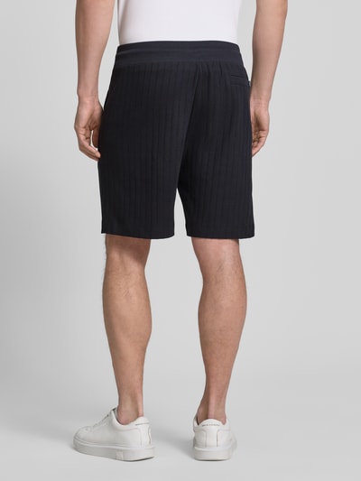 Männermodel trägt Regular Fit Shorts mit Tunnelzug Modell 'JUANITO' von JOOP! Collection in Dunkelblau, reine Baumwolle, Ganzkörperansicht Rückansicht.