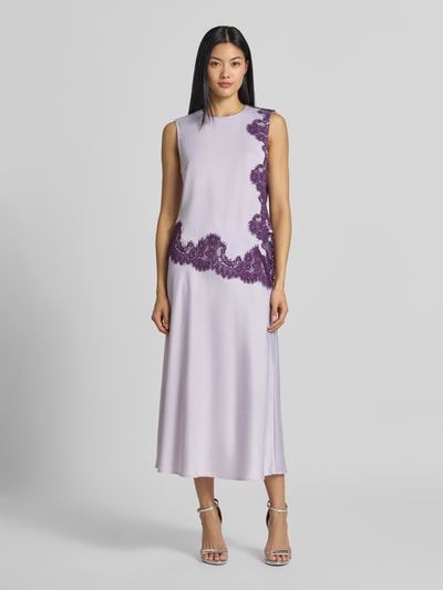 Vrouwenmodel draagt Midirok aus Satin Modell 'Pella' van YAS in lichtpaars satijn met a-lijn en elastische materiaalmix, licht glanzende textuur, bandwijdte maat S 36 cm, totale lengte 86 cm, volledige vooraanzicht.