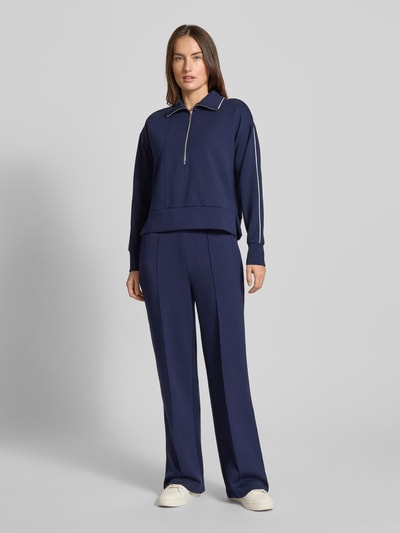 Frauenmodel trägt Sweatshirt mit kurzem Reißverschluss von Christian Berg Woman, Material-Mix mit Modal-Anteil, Umlegekragen, gerippte Abschlüsse, lockerer Schnitt, dunkelblau, Ganzkörperansicht von vorne.