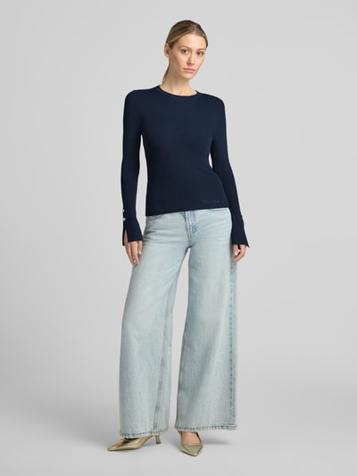 Vrouwenmodel draagt donkerblauw slim fit shirt met lange mouwen van viscosemix met strass-steentjes en logodetail, model 'Ellie' van GUESS, dames, model in jeans, geheellichaamsaanzicht van voren.