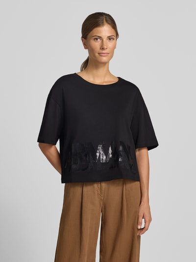 Vrouwenmodel draagt t-shirt met paillettenbesatz van Armani Exchange in zwart, puur katoen, los model, ronde hals, labelprint, ruglengte maat S 45 cm, geheellichaamsaanzicht van voren.
