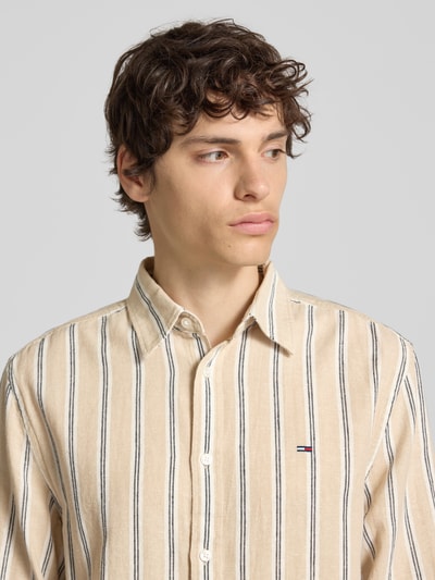 Männermodel trägt Regular Fit Freizeithemd aus Leinen-Baumwoll-Mix von Tommy Jeans, Mehrfarbig, Kentkragen, Gestreift, Nahaufnahme Oberkörper.