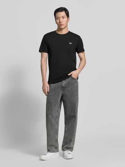 Männermodel trägt T-Shirt mit Logo-Patch und Rundhalsausschnitt von Emporio Armani, Reine Baumwolle, Modern Fit, Rückenlänge 69 cm, Ganzkörperansicht von vorne.