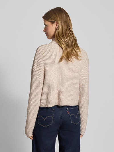 Frauenmodel trägt Relaxed Fit Rollkragenpullover mit Woll-Anteil Modell 'MELANIE' von Only, beige melierte Strickstruktur, gerippte Abschlüsse, Ganzkörperansicht Rückansicht.
