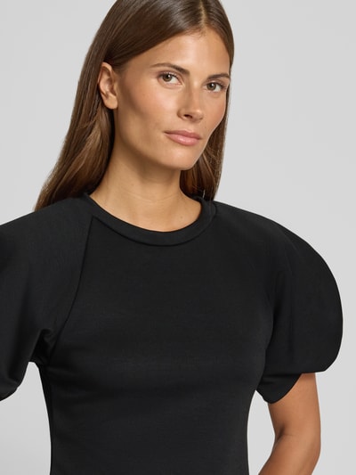Vrouwenmodel draagt Bluse mit Ballonärmeln van Rinascimento in zwart Materiaalmix met stretch, getailleerde pasvorm, ronde hals, Nahaufnahme bovenlichaam.