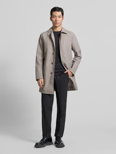 Männermodel trägt Mantel mit Knopfleiste von MCNEAL in Beige, lockerer Schnitt, Kentkragen, Eingrifftaschen, Ganzkörperansicht von vorne.