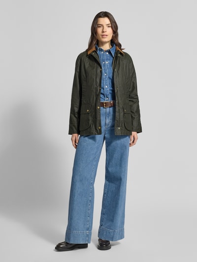 Frauenmodel trägt Wachsjacke aus reiner Baumwolle von Barbour in Regular-Fit-Optik, Umlegekragen, feine Webstruktur, Pattentaschen, Ganzkörperansicht von vorne.