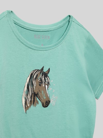 Mädchen trägt T-Shirt mit Motiv-Print und Rundhalsausschnitt von Blue Seven, Reine Baumwolle, Regular-Fit, Nahaufnahme Oberkörper.