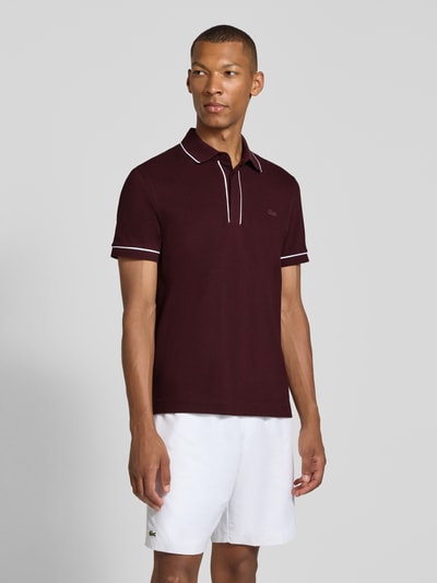 Mannelijk model draagt Regular Fit poloshirt uit katoenmix van Lacoste in bordeaux met witte accenten, heren poloshirt, geheel vooraanzicht.