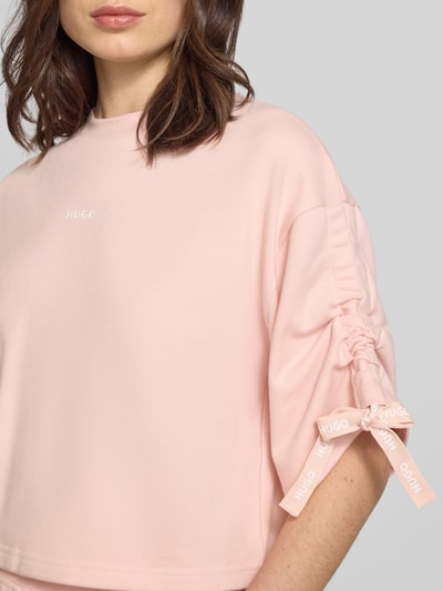 Frauenmodel trägt Boxy Fit Pyjama-Oberteil mit Baumwoll-Anteil von HUGO, Optik: Unifarben, Boxy-Fit, Cropped, Label-Print, Raffungen, Sweat, Nahaufnahme Oberkörper.