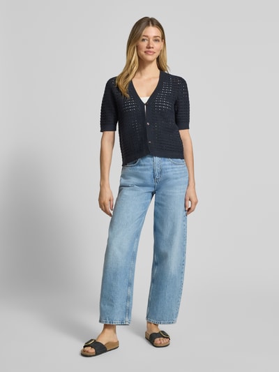 Frauenmodel trägt Regular Fit Cardigan aus Viskose-Mix Modell 'Dostal' von OPUS in Dunkelblau, Strick-Optik, semitransparent, durchgehende Knopfleiste, kurzärmelig, V-Ausschnitt, kombiniert mit weiter Jeans, Ganzkörperansicht von vorne.