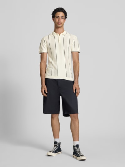 Männermodel trägt Slim Fit Poloshirt mit Knopfleiste Modell 'AVEN' von Blend, reine Baumwolle, schwarz-weiß, Ganzkörperansicht von vorne.
