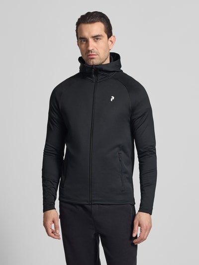 Männermodel trägt Slim Fit Jacke mit Logo-Print Modell 'Rider' von Peak Performance aus Elastischer-Material-Mix in Schwarz, Reißverschluss, Eingrifftaschen mit Reißverschluss, Stehkragen, Herren, Ganzkörperansicht von vorne.
