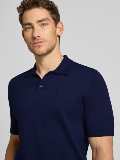 Männermodel trägt Slim Fit Poloshirt aus reiner Bio-Baumwolle von Armedangels, Optik: Unifarben, Feinstrick, Logo-Stitching, Nahaufnahme Oberkörper.