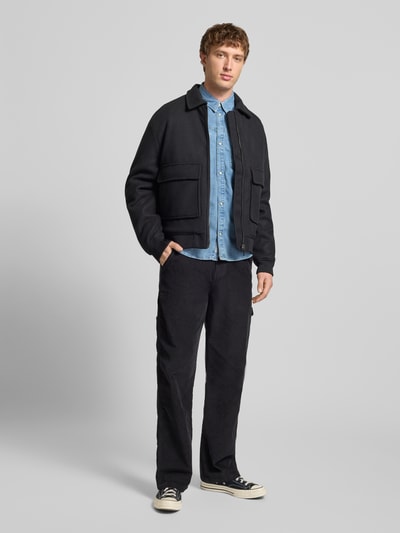 Männermodel trägt Regular Fit Jeanshemd aus reiner Baumwolle Modell 'BROOKS' von Pepe Jeans in hellblauer Denim-Optik, Ganzkörperansicht von vorne.