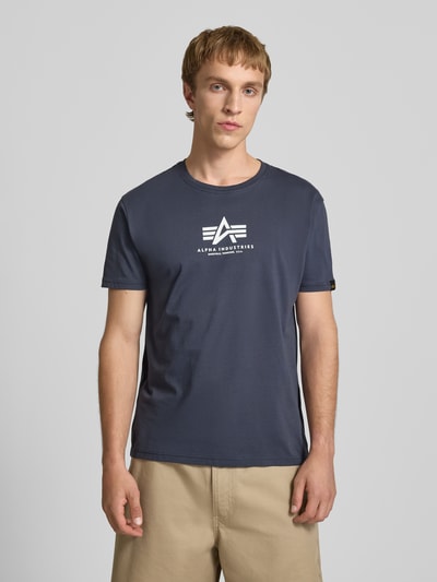 Männermodel trägt T-shirt met logoprint en ronde hals van Alpha Industries, puur katoen, regular fit, ruglengte maat M 67 cm, Ganzkörperansicht van voren.