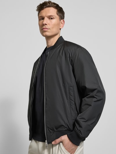 Männermodel trägt Regular Fit Bomberjacke mit Zweiwege-Reißverschluss Modell 'CHRIS' von Selected Homme, Optik: Unifarben, Ganzkörperansicht von vorne.