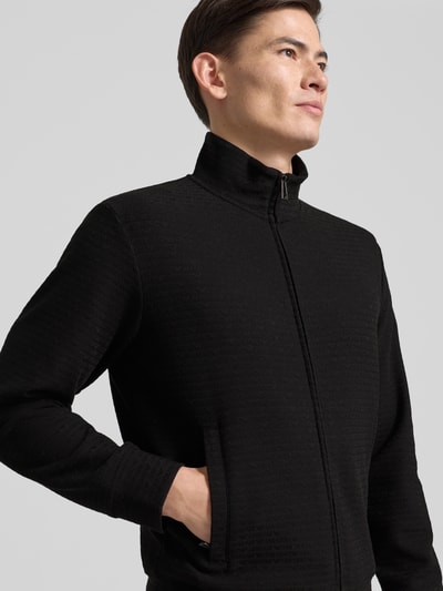 Männermodel trägt Sweatjacke mit Stehkragen von Emporio Armani, Schwarz, Baumwoll-Lyocell-Mix mit Stretch-Anteil, Reißverschluss, Eingrifftaschen, gerippte Abschlüsse, lockerer Schnitt, Rückenlänge 64 cm, Ärmellänge 60 cm, Nahaufnahme Oberkörper.
